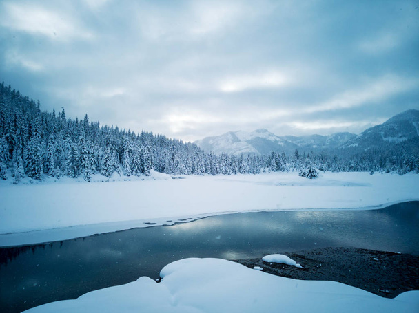 Снег покрыл замерзший красивый пруд Золотой ручей с заснеженными деревьями и тропой в течение зимы в дикой природе Альпийских озер в округе Киттиас штат Вашингтон
 - Фото, изображение