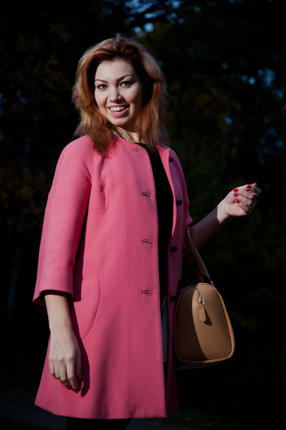 Beautiful woman in pink coat walks in the Park - Fotografie, Obrázek