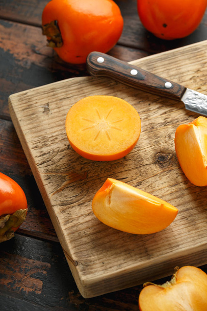 Raw ripe persimmons fruits slices on wooden board - Foto, imagen