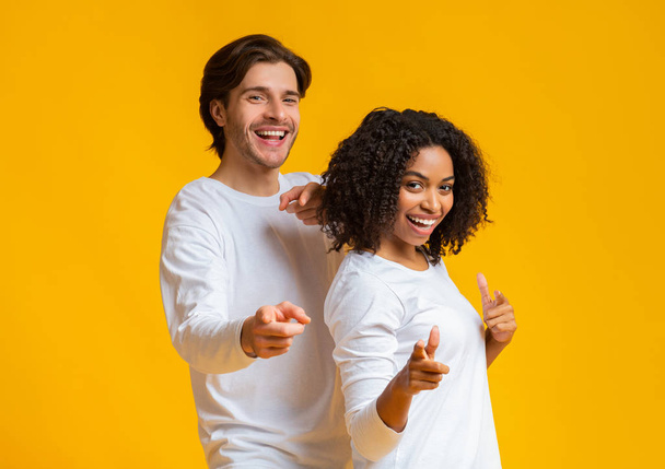 Cheerful guy and girl pointing at camera with fingers, choosing somebody - Foto, afbeelding