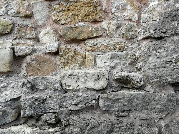 Stary mur ze skał. Średniowieczna powierzchnia z cegieł. Tekstura starego kamiennego szpilki z cementem. - Zdjęcie, obraz