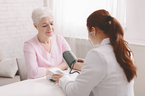 高齢女性患者の血圧を測定する医師 - 写真・画像