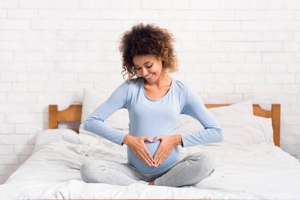 Kobieta w ciąży trzymając ręce w kształcie serca na dziecko bump - Zdjęcie, obraz