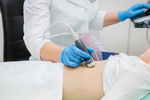 Ženský lékař pracující s ultrazvukovým skenerem vyšetřující pacientův žaludek. - Fotografie, Obrázek