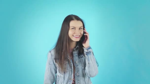 A young Smiling Woman in a Denim Jacket is Talking on the Phone and Laughing - Video, Çekim