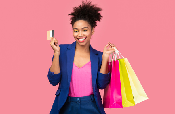 ショッピングバッグやプラスチックカードと陽気な黒人女性 - 写真・画像