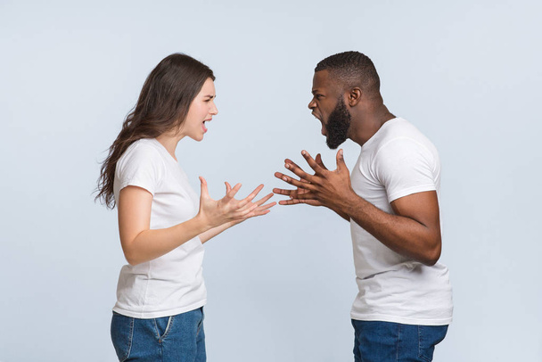 Angry interracial couple quarrelling, yelling at each other and emotionally gesturing - Foto, immagini