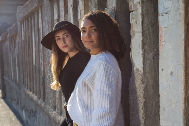 Retrato de un par de bellas chicas españolas de moda de pie contra una pared de textura. Fotografía de moda Street art
 - Foto, imagen