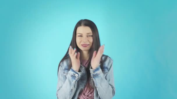 Young worried girl standing with fingers crossed for good luck and wins isolated over blue background - Záběry, video