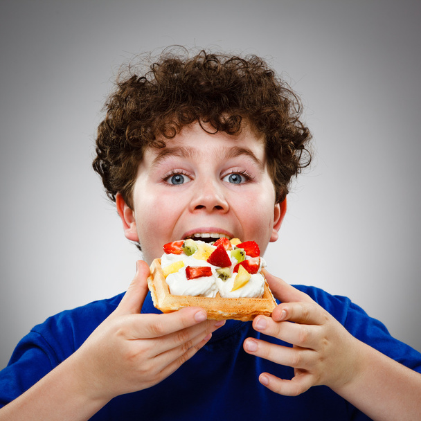 Boy eating cake with cream and fruits - Fotoğraf, Görsel