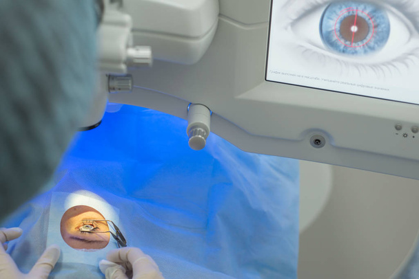 Doktor oftalmolog stisknutím tlačítka na ovládacím displeji spustí moderní laser pro korekci zrakového postižení. Laserová oční mikrochirurgie. - Fotografie, Obrázek