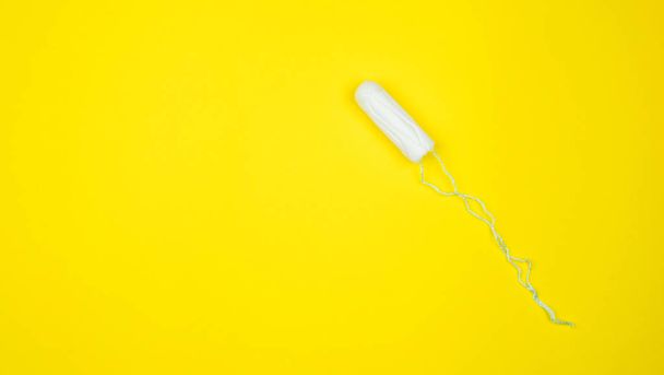 medizinischer weiblicher Tampon auf gelbem Hintergrund. hygienischer weißer Tampon für Frauen. Wattestäbchen. Menstruation, Mittel zum Schutz. Tampons auf rotem Hintergrund - Foto, Bild