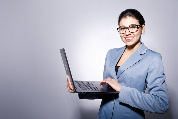 Веселая улыбающаяся предпринимательница в очках, держащая ноутбук
 - Фото, изображение