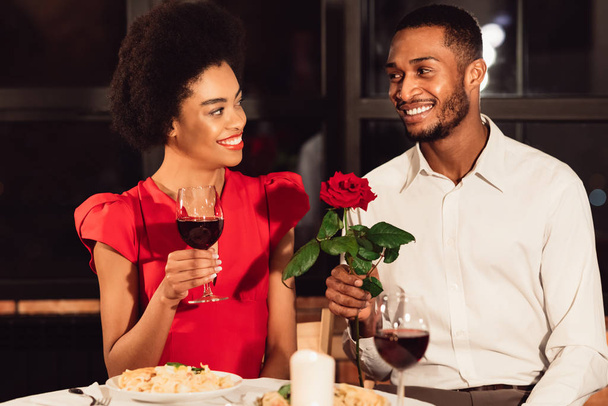 mężczyzna dając Rose dla kobiety mając Walentynki daty w restauracji - Zdjęcie, obraz