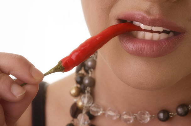 young woman eating red chili pepper - Фото, изображение