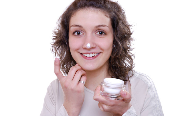 young woman applying moisturizer cream on her face - Foto, imagen