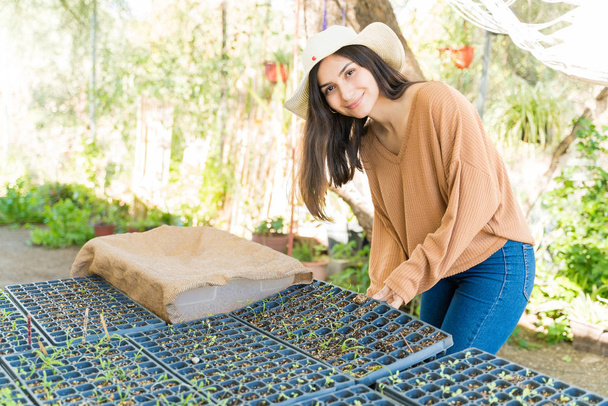Young Hispanic woman with seedlings tray standing at farm - Photo, Image