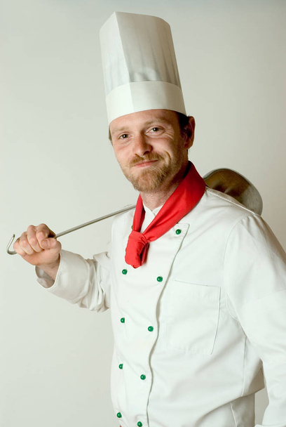 chef in uniform holding a knife and smiling - Foto, afbeelding