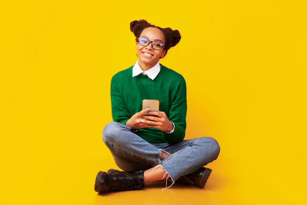 Felice adolescente nero seduto sul pavimento in studio
 - Foto, immagini
