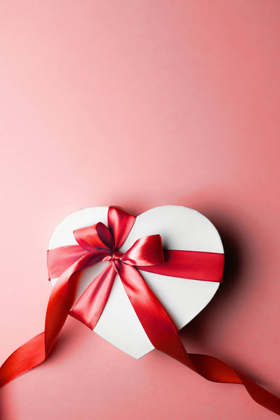 Valentinstag-Banner. herzförmige Geschenkschachtel mit rotem Band isoliert auf rot. Romantische Nachrichtenvorlage mit Kopierraum. - Foto, Bild