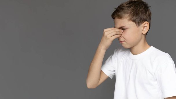 Εφηβικό αγόρι τρίβει τη μύτη του, αισθάνεται κουρασμένος, πανόραμα - Φωτογραφία, εικόνα