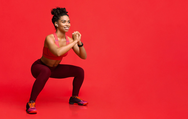 Ευτυχισμένο μαύρο κορίτσι απολαμβάνει την άσκηση πάνω από το κόκκινο φόντο - Φωτογραφία, εικόνα