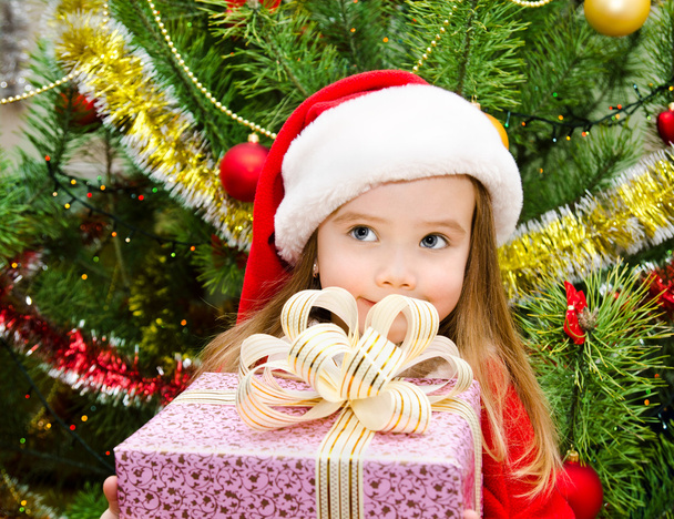 Little girl in santa hat with present have a christmas - 写真・画像