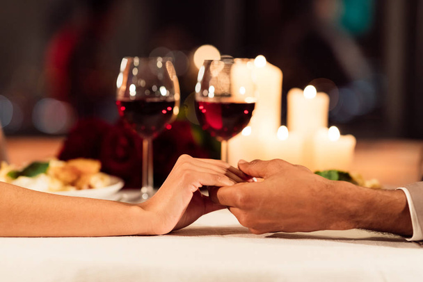 Closeup Of Couple Holding Hands On Served Restaurant Table, Cropped - Фото, изображение