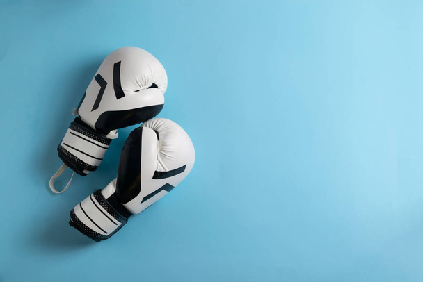 A pair of black and white boxing gloves on blue background with copy space for your text - 写真・画像