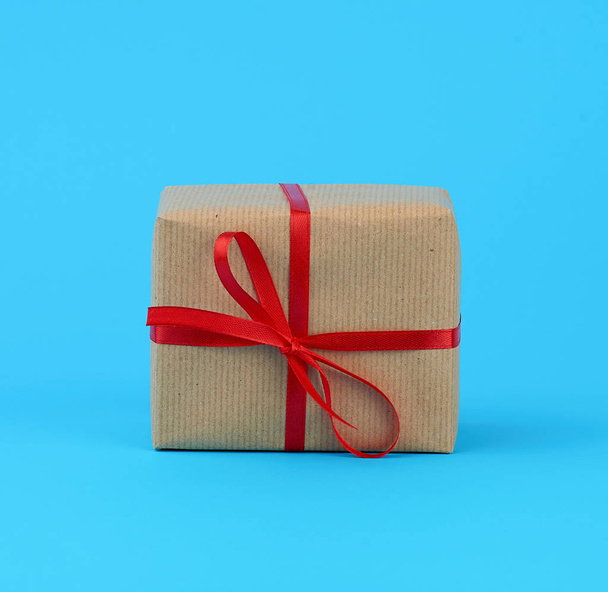 la caja se embala en papel kraft marrón y se ata con una seda delgada roja
 - Foto, imagen