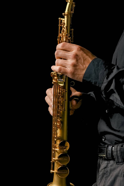 soprano saxophone in hands on a black background - Photo, image