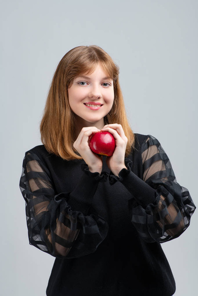 Girl posing in front of the camera with an apple in her hands - Фото, зображення