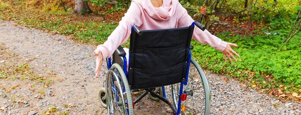 A fiatal, boldog, kerekesszékes nő a kórház parkjában élvezi a szabadságot. Mozgássérült lány rokkant székben mozgássérültek számára a természetben. Rehabilitációs koncepció. - Fotó, kép