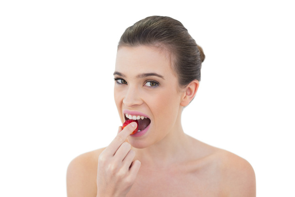 Attractive model eating a strawberry - Φωτογραφία, εικόνα