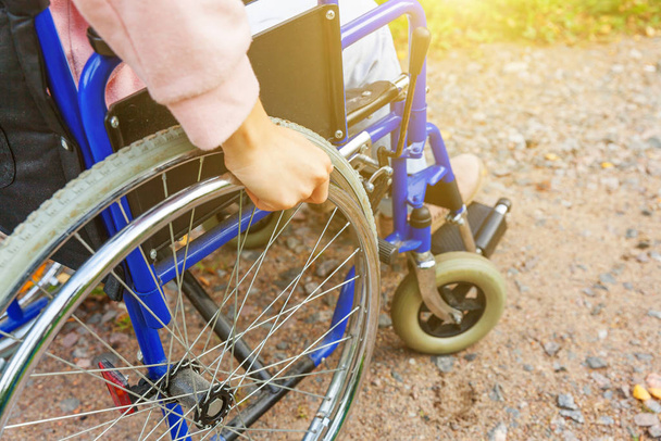 患者サービスを待っている病院の公園の道路上の車椅子の車輪のハンデの女性。屋外の障害者のための無効な椅子の認識できない麻痺した少女。リハビリテーションの概念. - 写真・画像