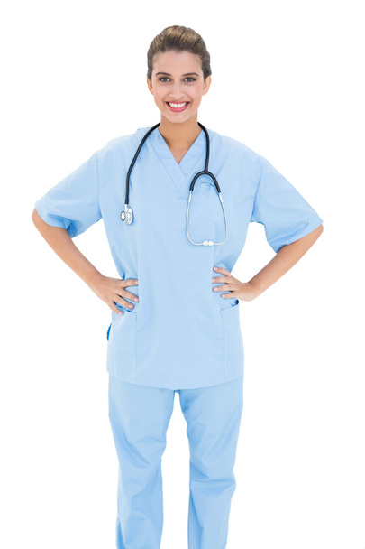Happy nurse in blue scrubs posing with hands on the hips - Foto, Imagen