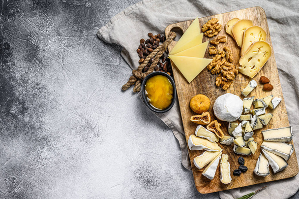 Sýrový talíř s francouzskými organickými sýry, fíky, ořechy na šedém pozadí. Horní pohled. Chutný sýrový předkrm. Mezera pro text - Fotografie, Obrázek