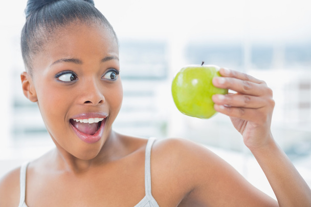 Happy woman holding and looking at green apple - Foto, imagen