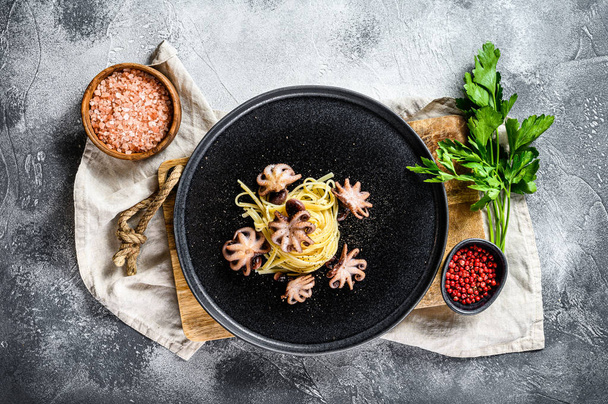 Těstoviny Bavetti s pečenou chobotnicí. Šedé pozadí. Horní pohled - Fotografie, Obrázek