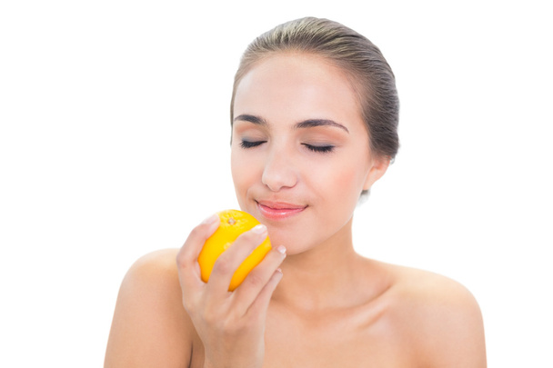 Smiling woman smelling on an orange - Foto, imagen