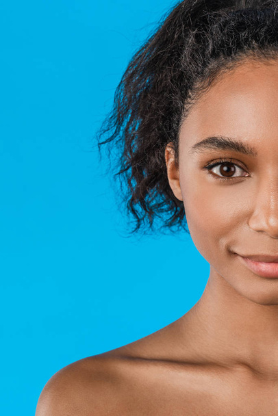 Vertical shot of half face american african beauty isolated on blue background - Фото, изображение