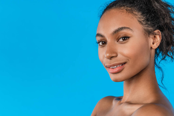Pretty girl with afro hairstyle smiling at camera on blue background - Foto, immagini