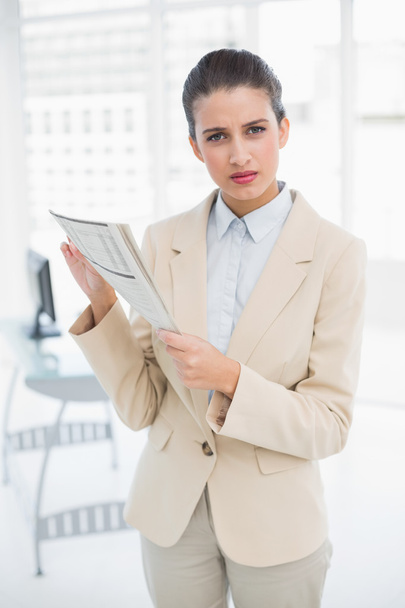 Frowning smart businesswoman holding a newspaper - Foto, afbeelding