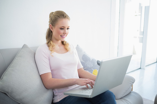 Casual content blonde sitting on couch using laptop - Foto, Imagem