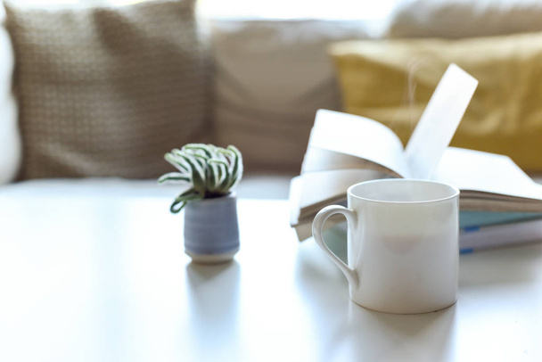 現代的な家庭でコーヒーテーブルとホットドリンク付きのリラックスしたソファエリア - 写真・画像