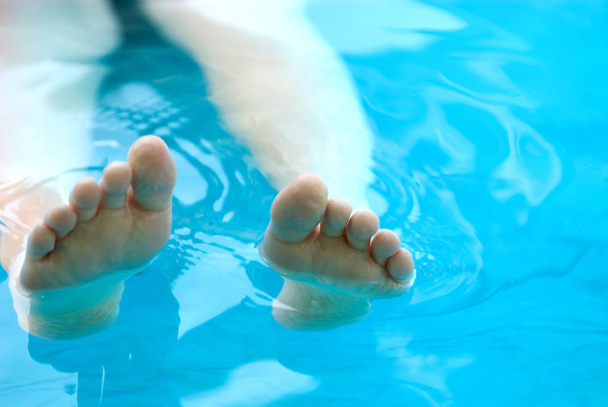 Feet lounging in a pool - Foto, Imagen