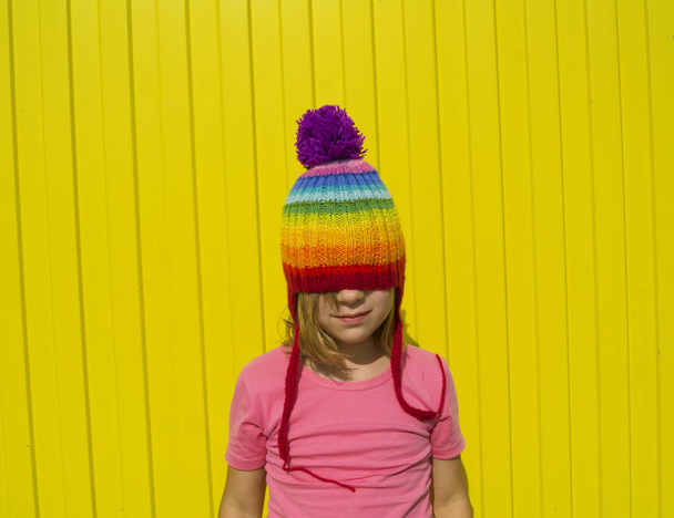 girl rainbow knitted hat yellow background - Foto, Bild