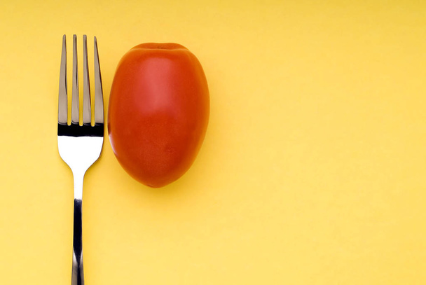 Fork and tomato on yellow - Foto, Imagen