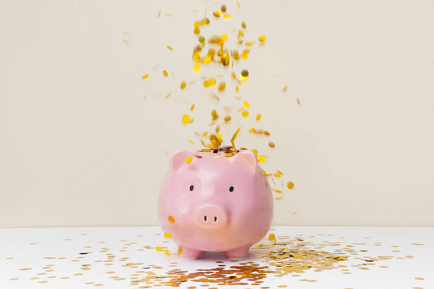 A lot of gold coins falling into a piggy bank - Foto, Imagen