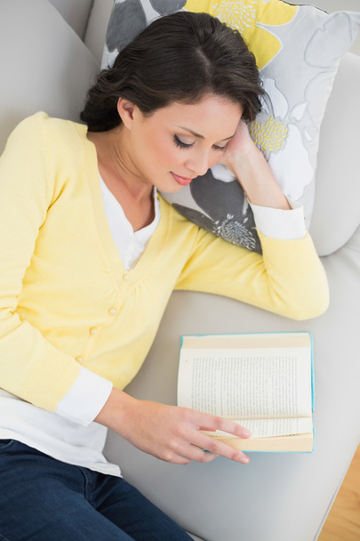 Peaceful casual brunette in yellow cardigan reading a book - Фото, зображення